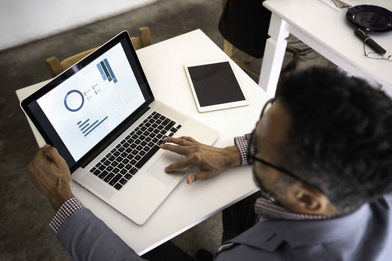 A man works on his computer, which has charts and graphs on it