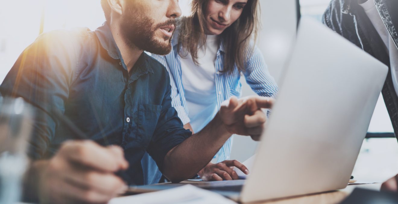 Two people at a desk reviewing a laptop screen
