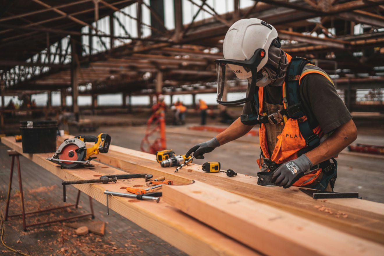 A person in protective gear saws and drills wood on a job site