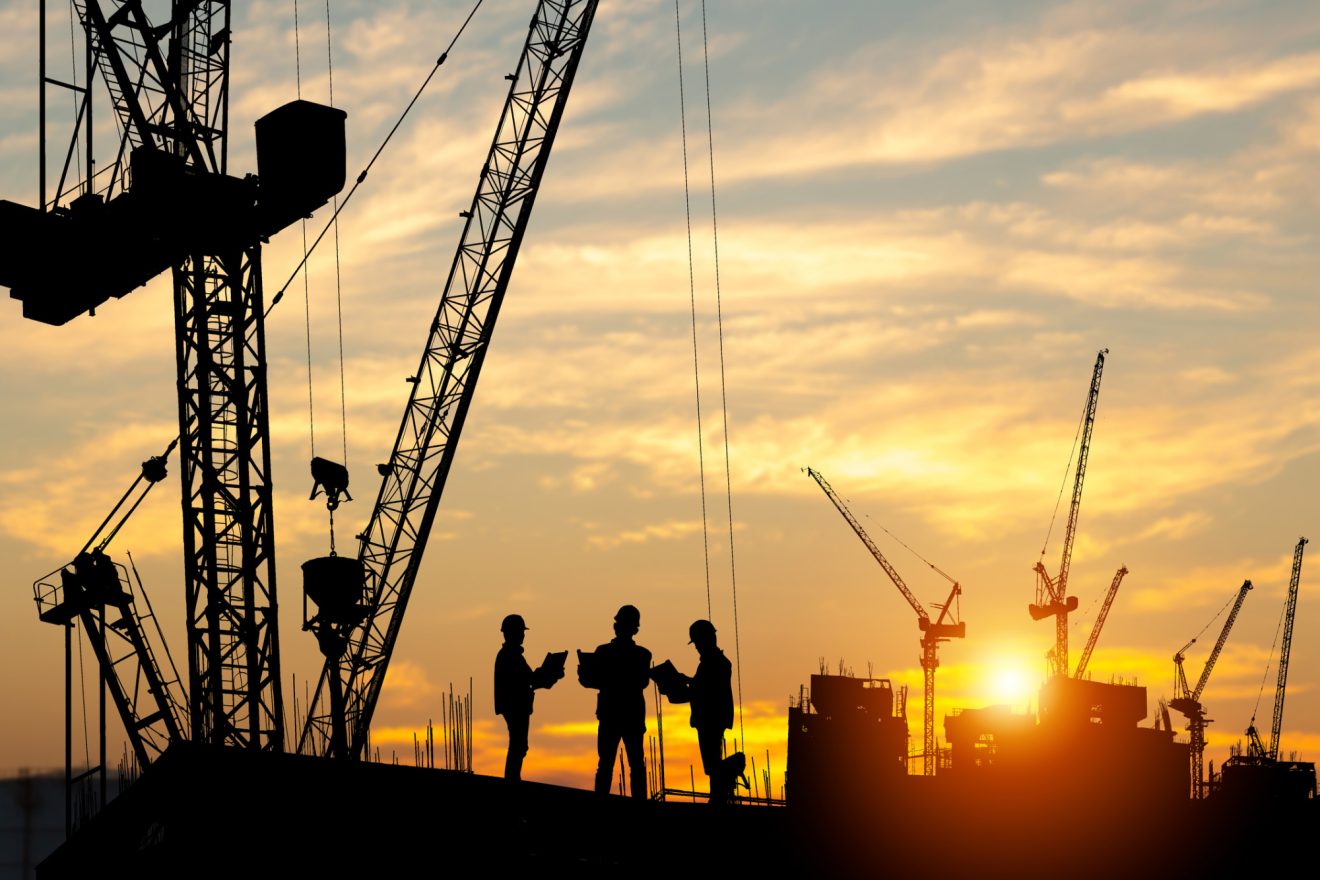People and construction equipment silhouetted against a sunset