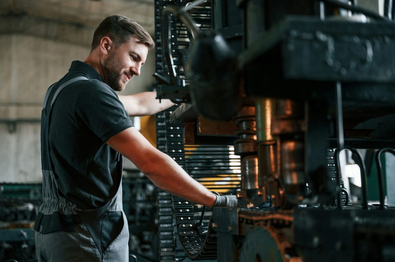 A man performs maintenance on a piece of manufacturing equipment