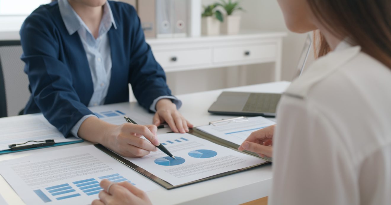 Two people sitting a desk reviewing graphs and charts in a presentation