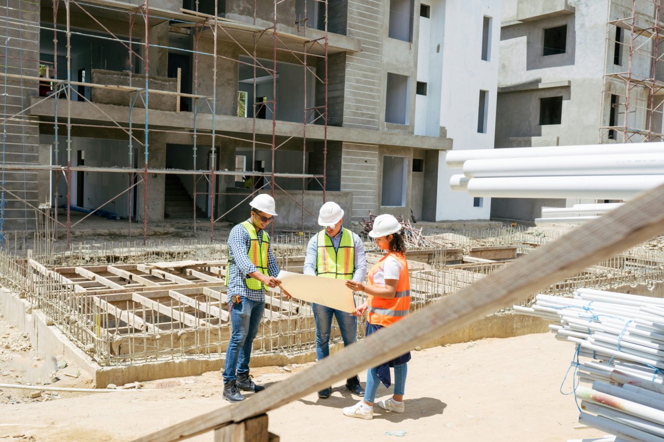 Three people look at project plans on a job site