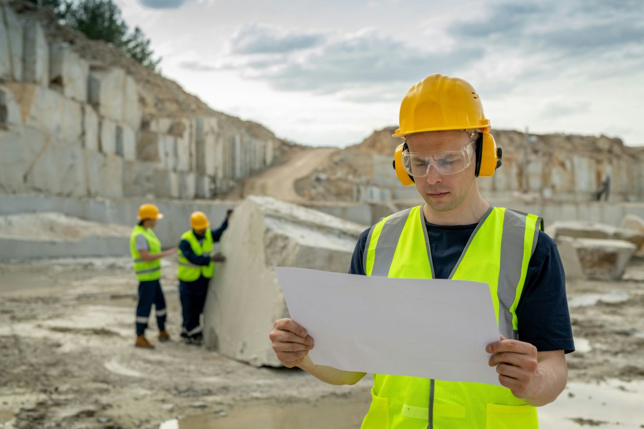 One person references notes on a job site while two others work behind him.