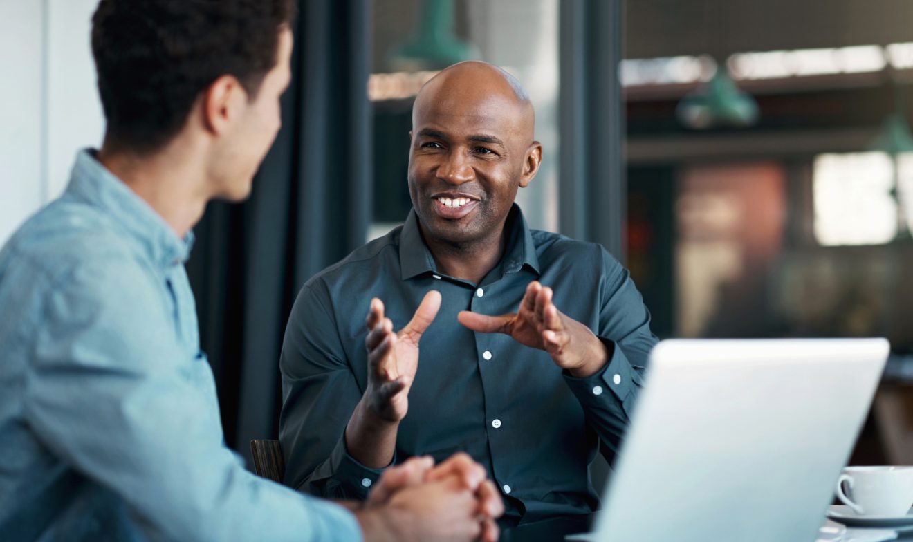 Two men smile and talk at a table