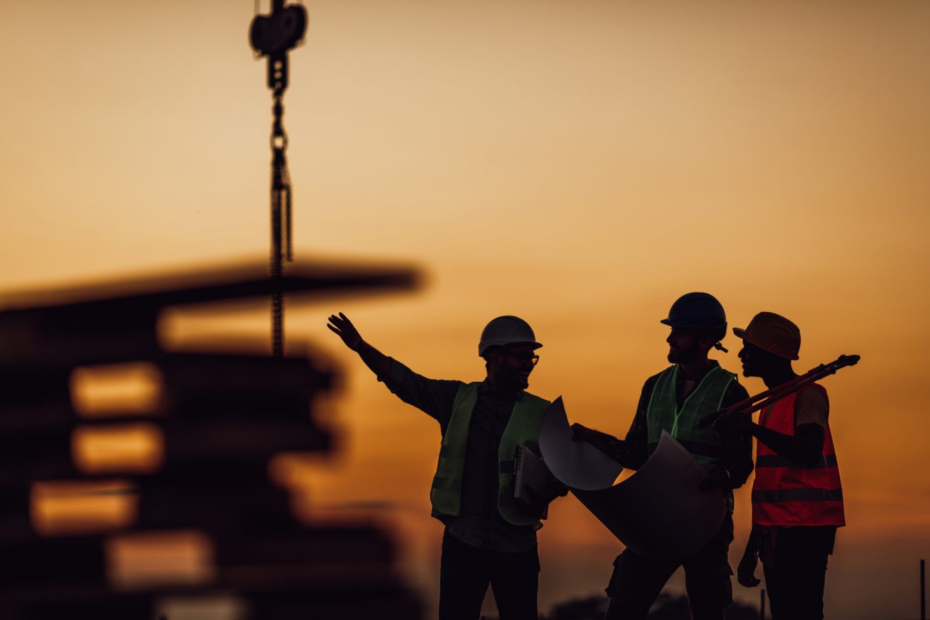 Construction workers looking at the site at sunset