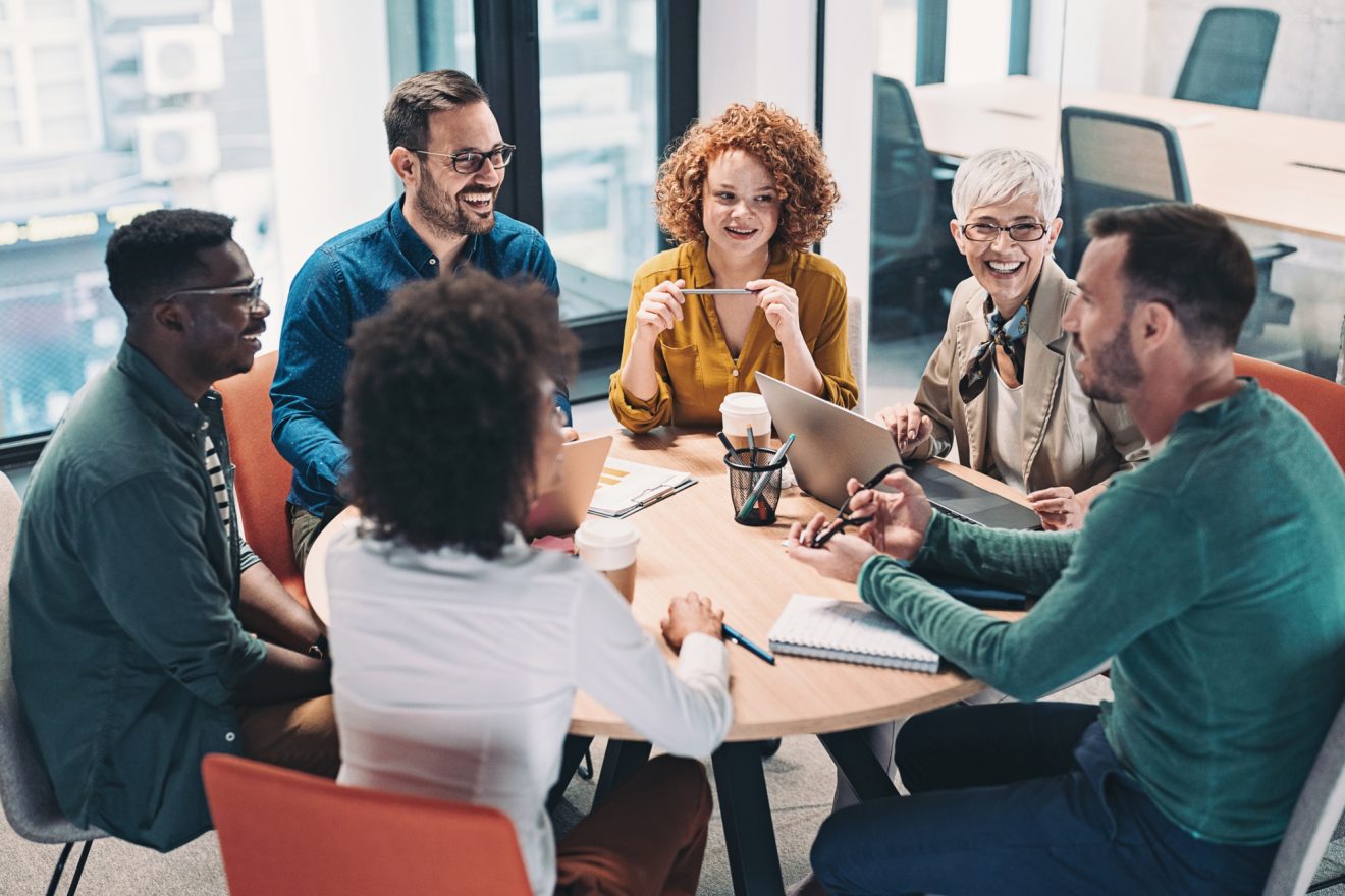 group of business people sitting around a table and talking
