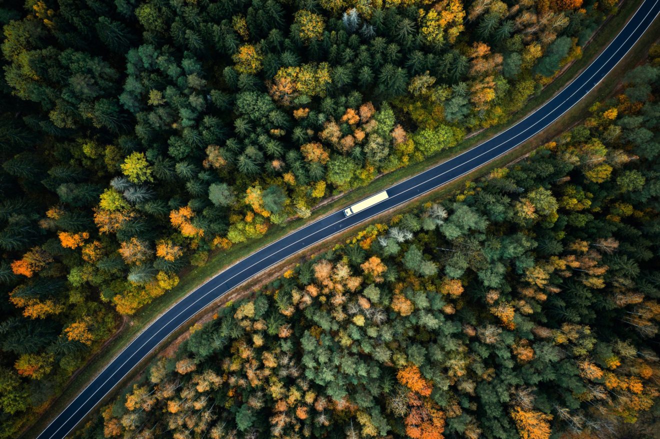 An aerial view of a semi truck driving on a windy road