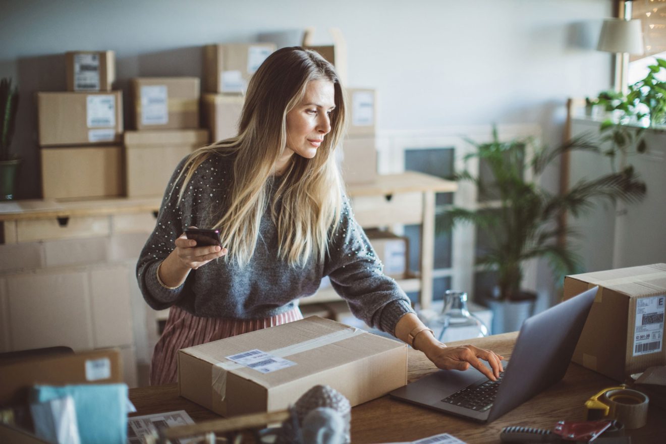 A woman references Quickbase while looking at a package